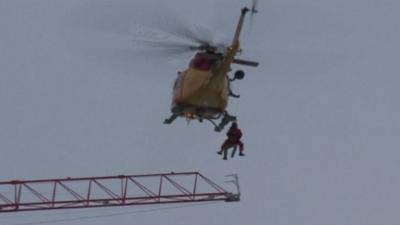 The helicopter lifts the man to safety