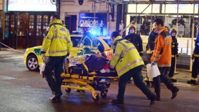 An injured person on a stretcher outside the Apollo Theatre