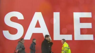 People walk past a sale sign