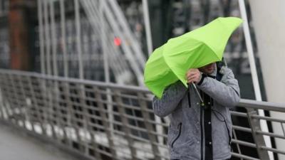 A man struggles with his umbrella