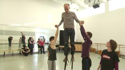 Colin Paterson being taught how to use stilts by Northern Ballet's circus skills team