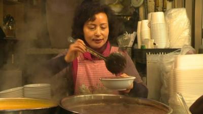 A lady serves red bean porridge in Seoul's Kwangjang Market