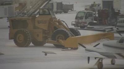 Snow plough on runway near small planes