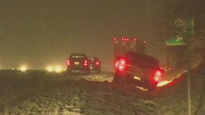 Cars driving - and on the side of the road - in heavy snow in Virginia, US