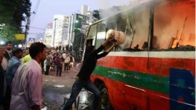 A Bangladeshi resident throws water onto a burning bus in Dhaka on January 2, 2014