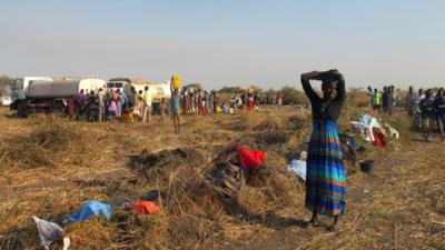 Displaced South Sudanese people filling cans with water from a UN tanker