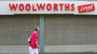 Woman walks past Woolworths shop front