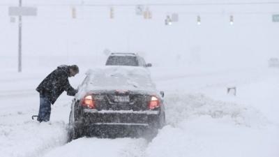 A motorist helps dig out a driver stuck in a snow drift Sunday, Jan. 5, 2014, in Zionsville, Ind