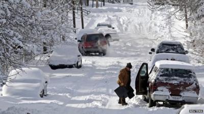 A man clears snow from his car in Indianapolis, Indiana January 6, 2014