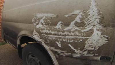 Mountain scene on a muddy white van