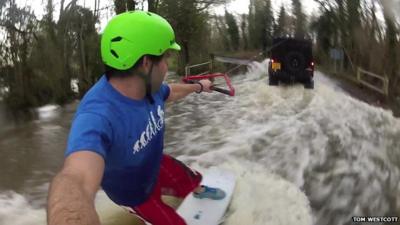 Man wakeboards down flooded road