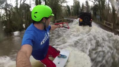 Man wakeboards down flooded road