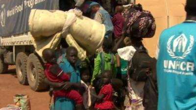 People carrying belongings load into a lorry