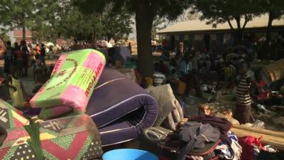 Mattresses and people in a refugee camp