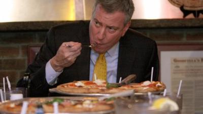 New York Mayor Bill de Blasio eating a pizza