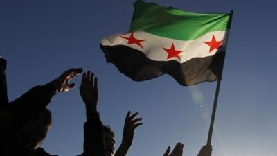 Syrian refugees hold the Syrian opposition flag