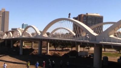 Biker rides along the top of a curved bridge