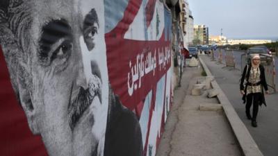 A Lebanese woman passes a portrait of slain Lebanese Prime Minister Rafik Hariri
