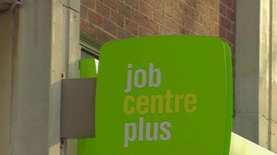 A green sign outside a London Job Centre reading 'job centre plus'