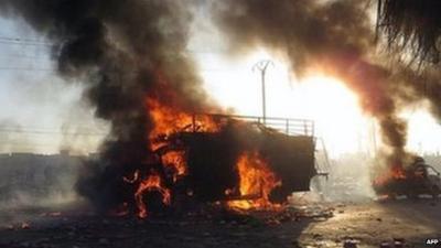 A Syrian man (left) runs next of a burned truck that was attacked by a Syrian forces helicopter in Aleppo (18 January 2014)