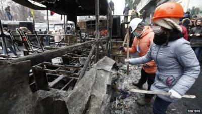 Women drum on a burnt vehicle as demonstrators gather at a barricade during a rally held by pro-European integration protesters in Kiev January 21