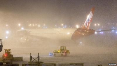 A plane shrouded by snow at JFK Airport, New York