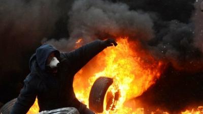 A Ukrainian demonstrator stands amid burning tyres during clashes in central Kiev