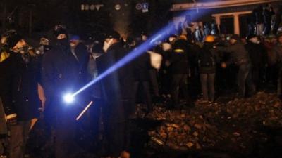 Anti-government protester uses a flashlight during a rally in Kiev