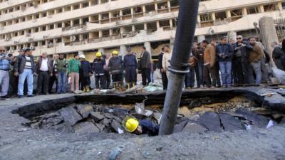 An Egyptian fire fighter checks a crater made by a blast at the police headquarters in Cairo