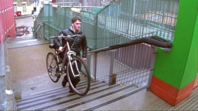 Man carrying cycle up steps