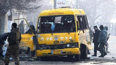 Afghan policemen inspect the wreckage of a bus hit by a suicide attack in Kabul