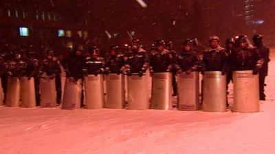 Riot police stand guard in the snow