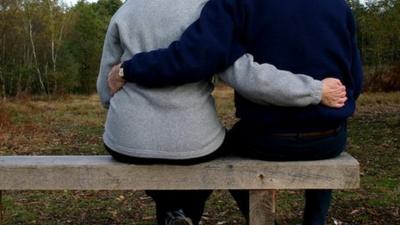 Couple embrace on park bench