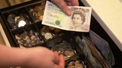 A supermarket checkout worker gives change