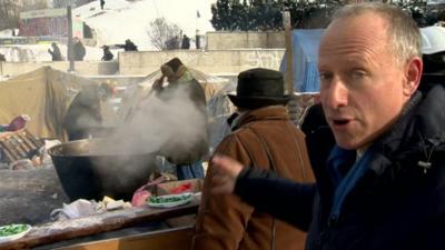 Steve Rosenberg pointing at food stall in Kiev