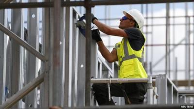 A construction worker assembles metal frames at a housing development project in south London