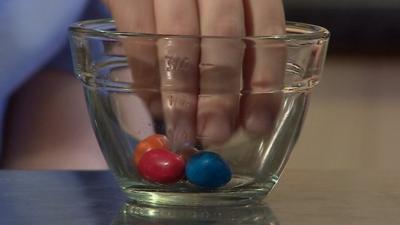 Hand in bowl containing chocolate peanut sweets