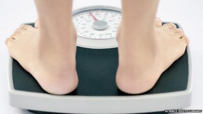 A young slim woman weighs herself on bathroom scales