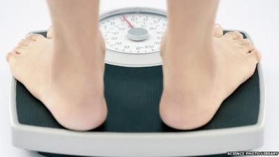 A young slim woman weighs herself on bathroom scales