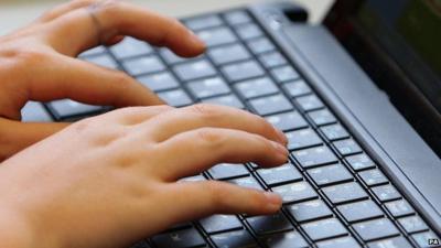 A young teenager types on a computer keyboard