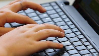 A young teenager types on a computer keyboard