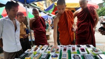 Buddhist monks look at mobile phones