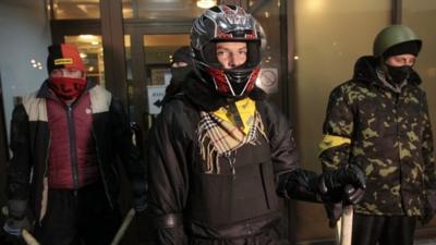 Opposition activists stand guard near the entrance to a private hospital where activist Dmytro Bulatov