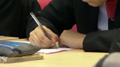 Student writing at a desk