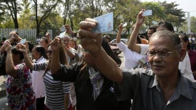 Pro-election supporters hold up their ID cards to demand to vote outside Din Daeng polling station in Bangkok Sunday, Feb. 2, 2014