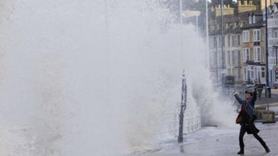 Man holds up his arm as a wave crashes inland