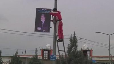 Man hanging candidate poster from lamppost