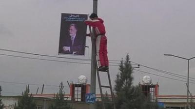 Man hanging candidate poster from lamppost