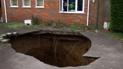 Phil Conran looks out of a window from his home at the sinkhole