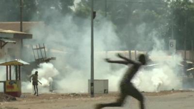 Figures running and smoke rising from street